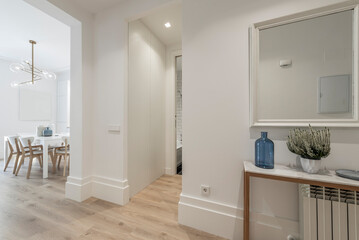 Entrance hall and housing distributor with light wood flooring, white wood carpentry, metal and marble sideboard and mirror and entrance to several rooms