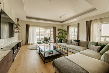 living room with sofas and a large glass top side table and windows leading out to a terrace in a luxury home