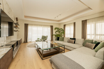 Fototapeta premium living room with sofas and a large glass side table and windows opening onto a terrace with the curtains drawn in a luxury home