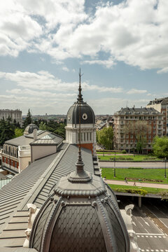 Metal domes with spiers and lightning rods on the roof of a mansion overlooking beautiful gardens and old buildings