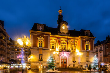Scenic night view of Chambery town hall in central square during winter Christmas season with bright lighting and traditional decorations, France