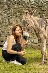 Girl with donkey, farm animals, having fun together, outdoors.