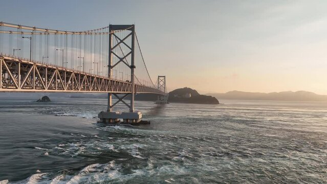 Slow move over fast moving tide under Naruto suspension bridge at sunset