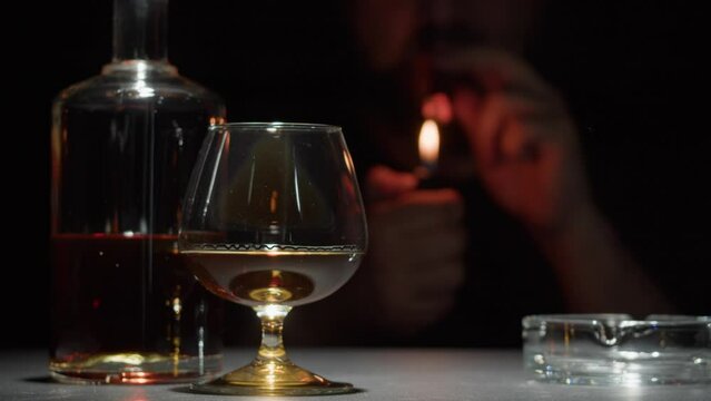 Brandy or whiskey and cigar close-up. Rich man smoking cigarette. Luxury cognac on black background. Alcohol amber drink, drinking rum, liqour beverage in glass.