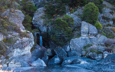 cascada entre rocas erosionadas por el agua, rocoso, grandes rocas, arboles, y arbustos verdes, en cascada entre rocas, rio 