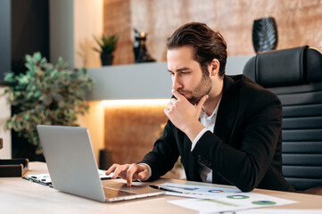 Focused successful caucasian smart business man, manager, business leader, sits at the workplace in...