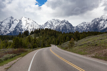 Scenic Road surrounded by Mountains and trees in American Landscape. Spring Season. Grand Teton National Park. Wyoming, United States. Nature Background.