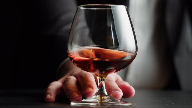Drinking brandy or whiskey close-up. Rich man drinks luxury cognac. Barkeeper giving alcohol amber rum, liqour beverage in glass.