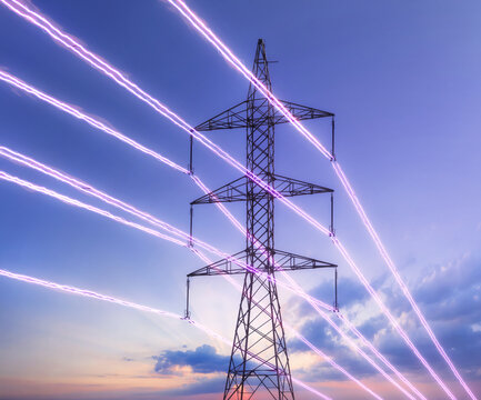 Electric transmission tower with glowing wires against the sunset sky. Energy concept.