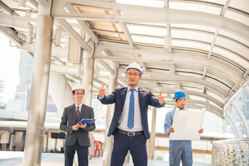 Civil engineer teams meeting working together wear worker helmets hardhat on construction site in modern city. Foreman industry project manager engineer teamwork. Asian industry professional team