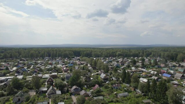 There are many residential houses and households in nature of Ural, Russia. Beautiful summer landscape at during daytime. Aerial view from a drone