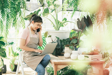 Young woman gardener is standing in the garden to contact customers.