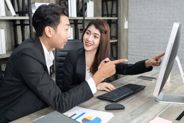 businessman showing something to colleague on desktop computer in office. Business man and woman working together 