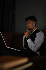 Fototapeta na wymiar Thoughtful Asian businessman looking at laptop screen, planning a business strategy