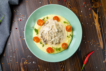 Stroganoff with beef, mushrooms and mashed potatoes on plate on wooden table