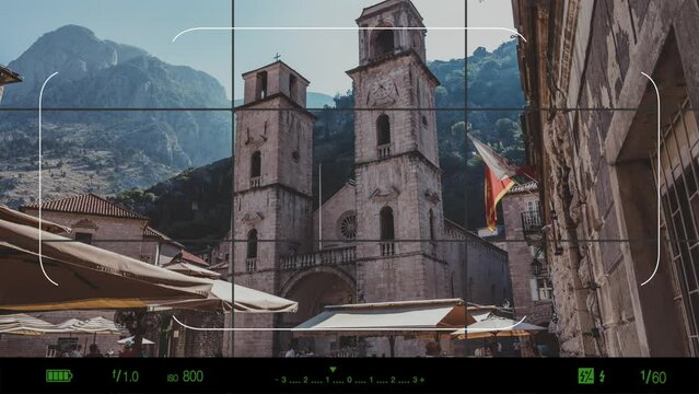 A look through photo camera at Cathedral of Saint Tryphon in Kotor, Montenegro is one of two Roman Catholic cathedrals in Montenegro. Summer landscape with mountain and sky in sunset time