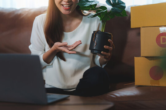 Image Of Young Asian Woman Startup Freelance With Flower And Showing To Customer By Computer Laptop. Online Marketing Packing Box Delivery Concept.