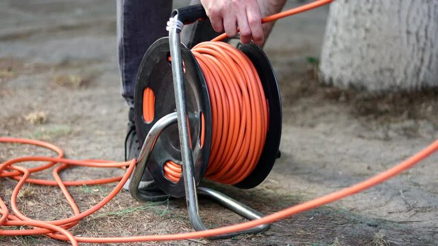A man winds the cable with electric cable reel
