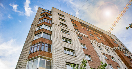 The facade of a modern residential brick house and the boom of a construction crane - the concept...