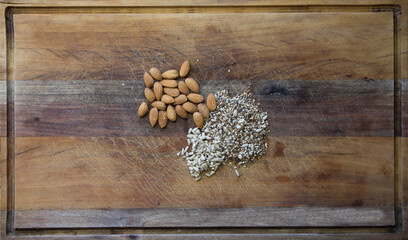Overhead shot of sunflower seeds and almonds scattered on a wooden table