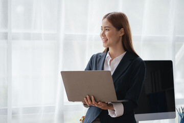 Young business women working and typing on laptop with happy and smile face on office spec.