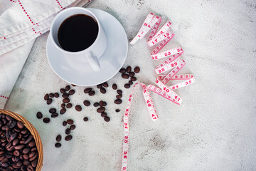 Cup of coffee and coffee beans background with measure tap on white desk.