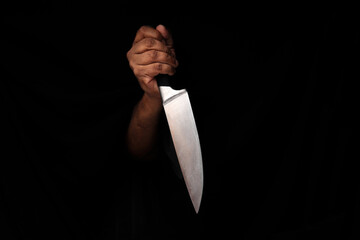 Asian male dark skinned single hand fist finger on black background holding stainless steel knife - Powered by Adobe
