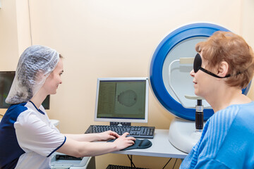 A girl optometrist examines the eyes of a patient using special modern equipment