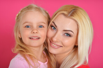 Close-up portrait of a charming little girl hugging with mom at home