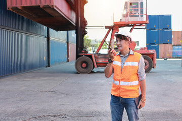 Fototapeta na wymiar Foreman using walkie talkie radio and tablet control loading containers box. Engineer or worker with safety hat work at container cargo site and checking industrial container cargo freight ship.
