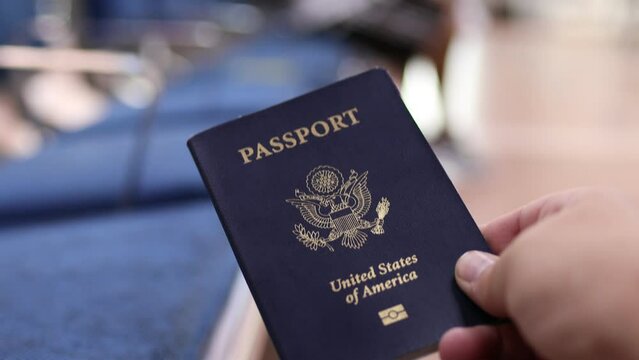 Hand holding a blue American passport inside an airport