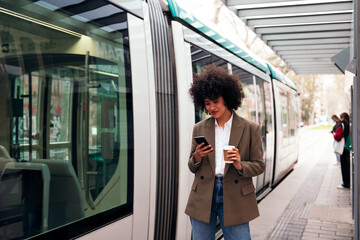 young business woman checking her phone while waiting for the tram to arrive, concept of technology...