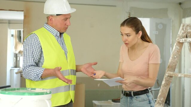  Woman architect and man builder quarreling about documentation problem in construction site.