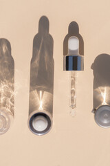 close up of pipette with pouring liquid serum with bottles and graphic shadows