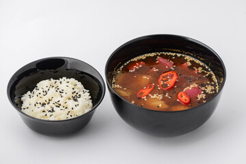 Thai dish vegetarian soup with tofu on a black plate and a plate of rice