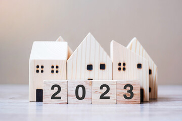 2023 Happy New Year with house model on table wooden background. Banking, real estate, investment,...