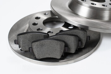 Set of new brake discs and brake pads against white background close-up. Selective focus on brake...