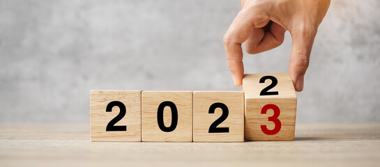 hand flipping block 2022 to 2023 text on table. Resolution, strategy, plan, goal, motivation,...