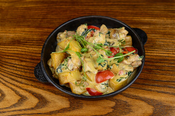 baked potatoes with vegetables in a pan on a wooden background
