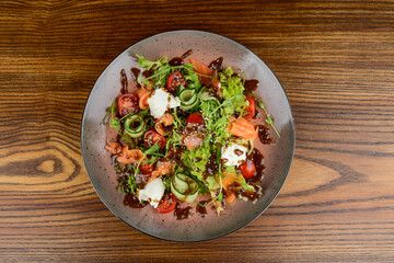 fresh salad with salmon in a brown plate top view