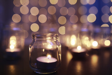Background with candles in glass vessels. Candles burn in a dark place. Rest in peace.