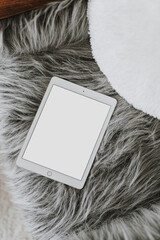 Flatlay tablet pad on fluffy woolen chair. Aesthetic elegant blog, social media, online store...