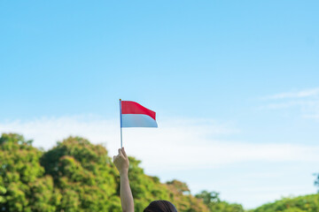 hand holding Indonesia flag on blue sky background. Indonesia independence day, National holiday...