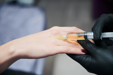Close up of woman's arm, which piercing with syringe to inject special substances to rejuvenate skin and to stop process of senescence. Professional injectable cosmetology.