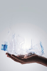 Hand with used plastic bottle and dispersion effect. Concept of plastic recycling.