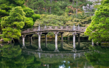 Fototapeta na wymiar Historic stone bridge at Gonaitei garden on beautiful autumn day in Kyoto Imperial palace in Kyoto, Japan. Oike-niwa - serene japanese zen garden and pond