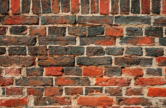 The texture of the wall of red and black burnt bricks in high resolution. Close-up with copy space for text. Idea for advertising, banner background or product article