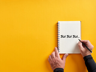 Male hand writing bla bla bla on a notepad. Business concept for talking too much with false...