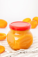 Apricot jam in glass jar. Homemade orange marmalade or jelly on white background. Natural fruit preserve for healthy baby food.