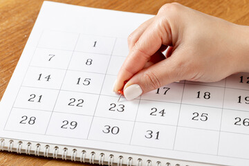 beautiful female Hand with manicure pushes a red pin on a calendar 23 day